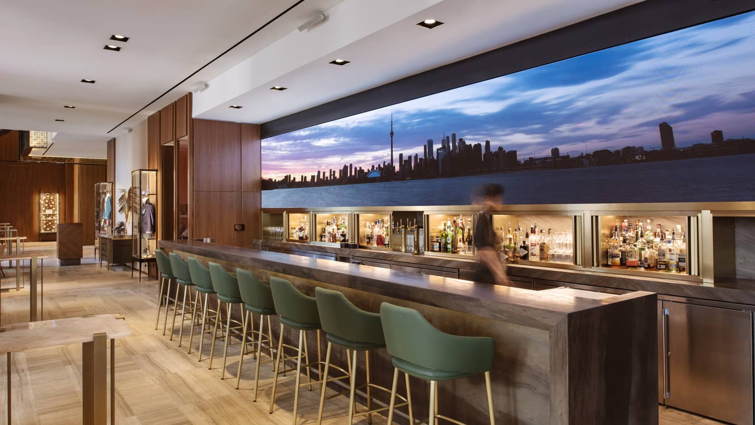 Upholstered chairs lined at a bar with a large image of the skyline