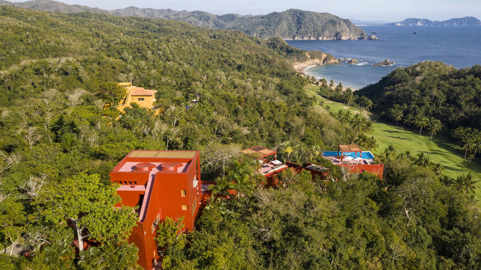 Aerial view of red private villa nestled within a jungle, close to Tamarindo coastline and beach