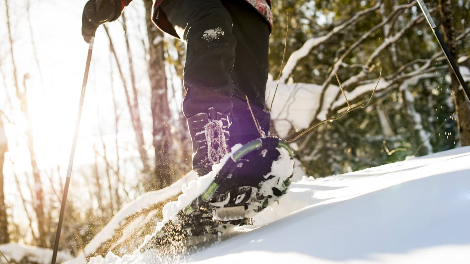 A person walking on snow using snow shoes and poles to help them walk.