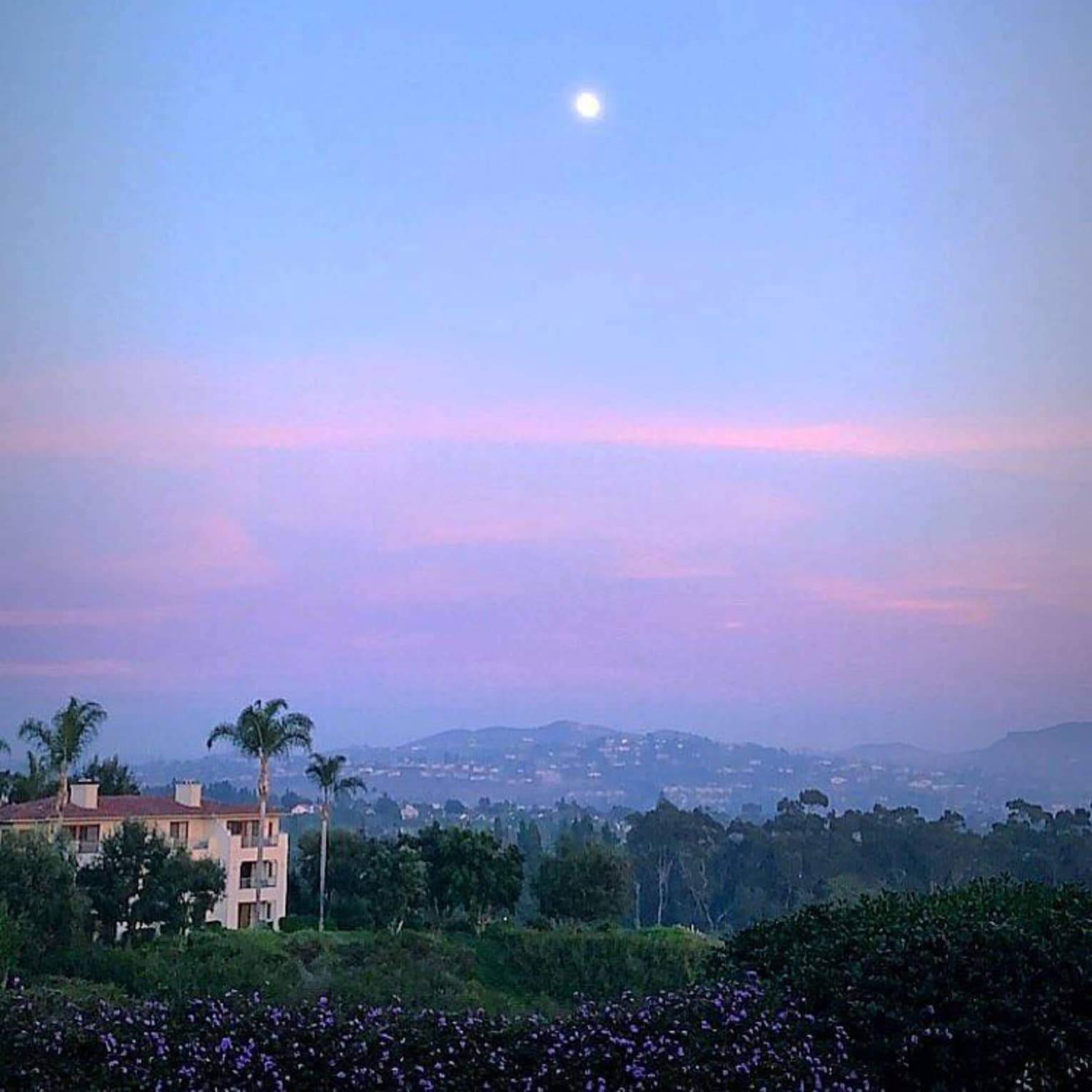 Sunset over sweeping view of mountains, resort and palm trees