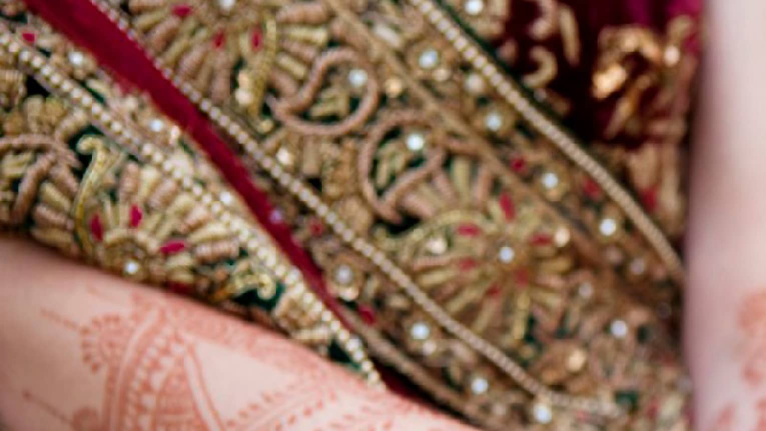 Indian wedding ceremony, bride with henna designs on arm holds groom's hands