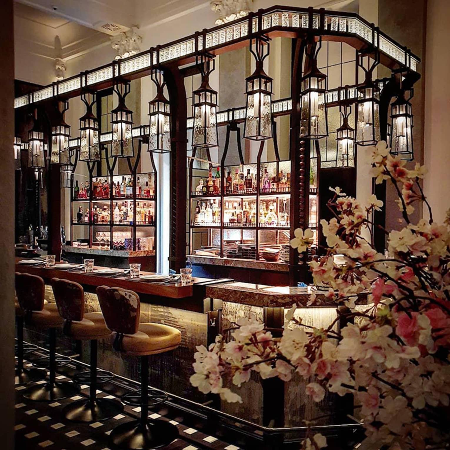 Elegant bar featuring vintage lanterns, hanging lights, stools and beautiful orchids