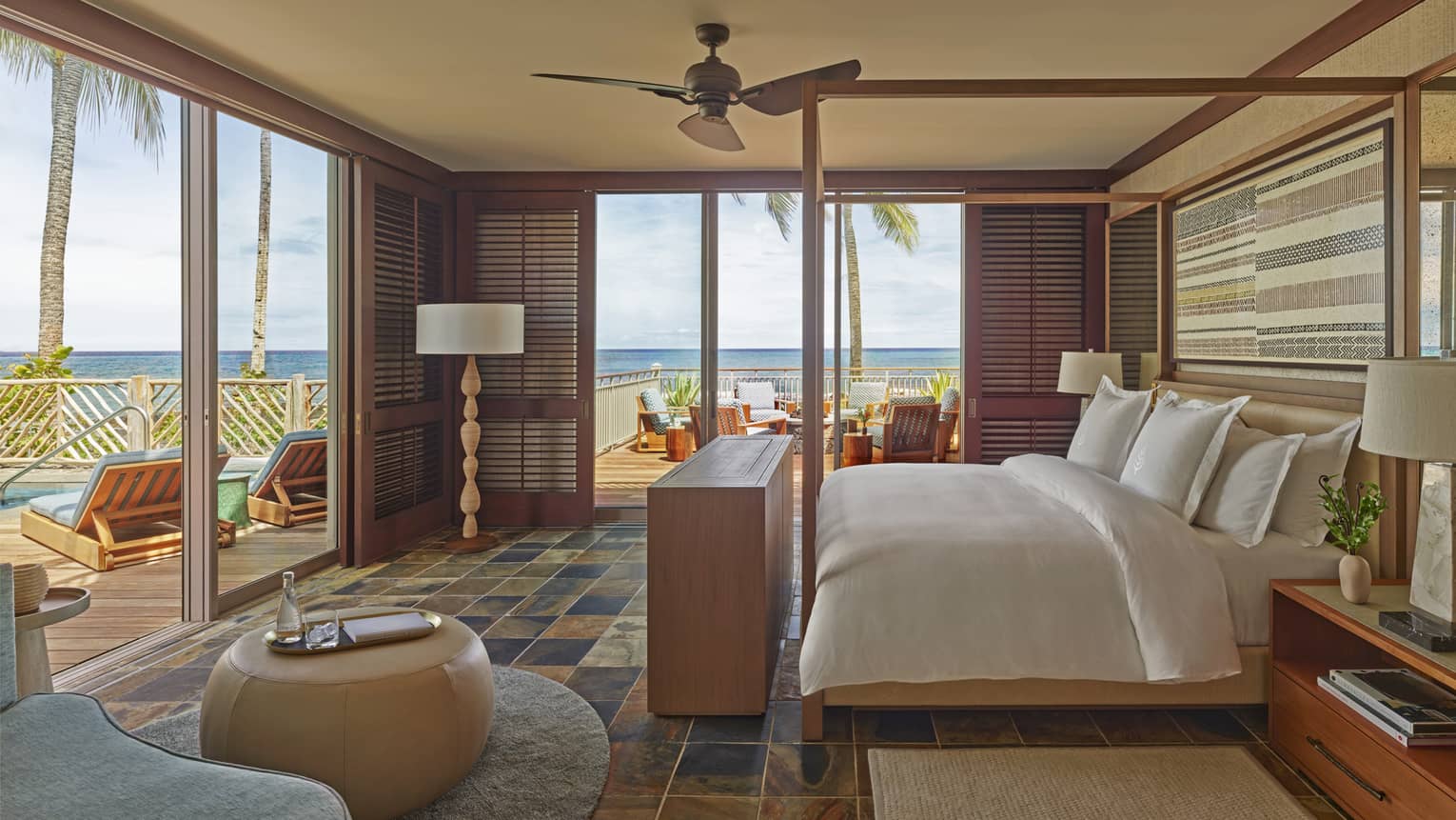 Bedroom with four-poster bed, sliding glass doors on two walls opening to tropical patio