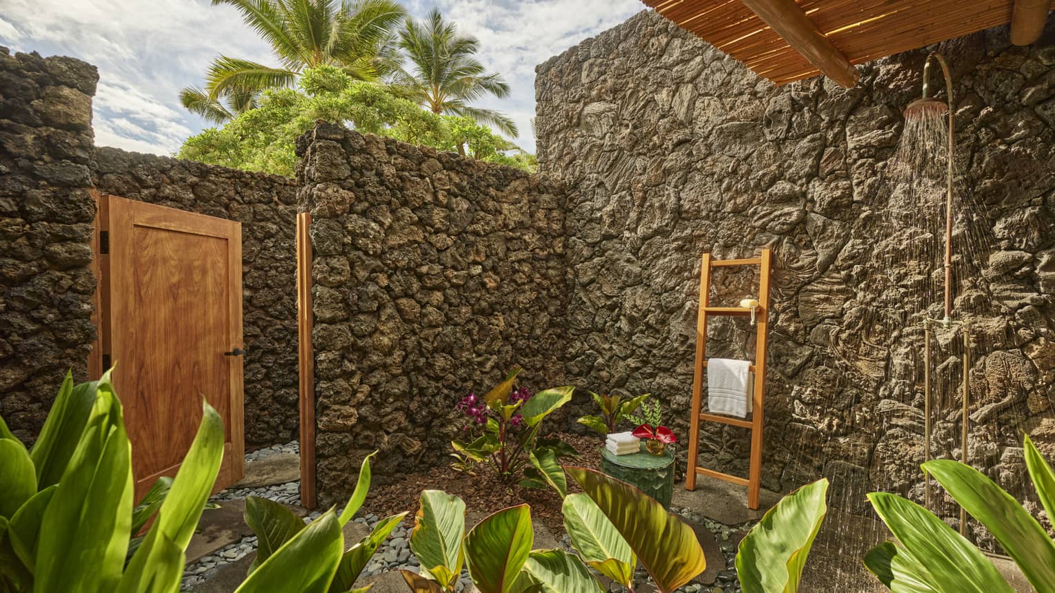 Outdoor lava rock shower and tropical plants