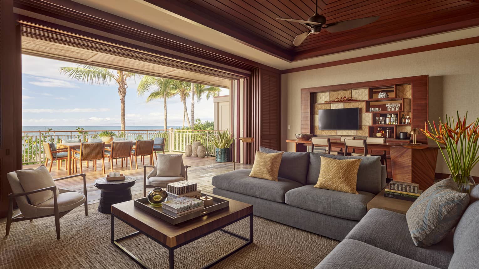 Living room with modern grey sofa, square coffee table, wall opening to tropical patio
