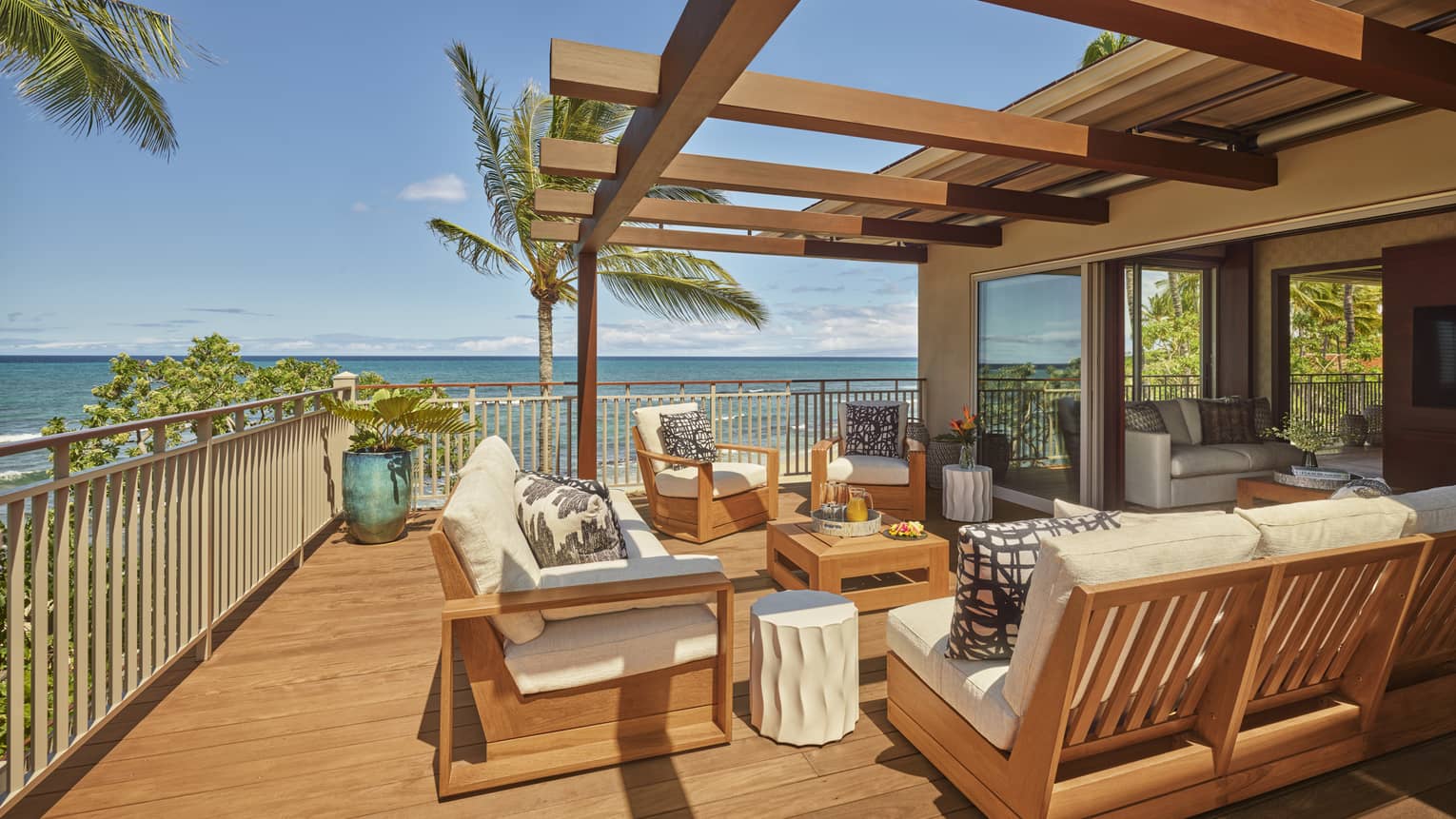 Outdoor wooden deck and wooden patio furniture with white cushions, ocean view