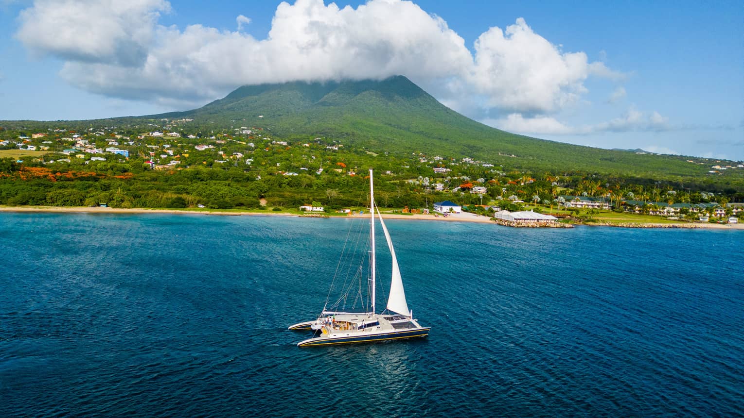A sail boat on water near a shore.