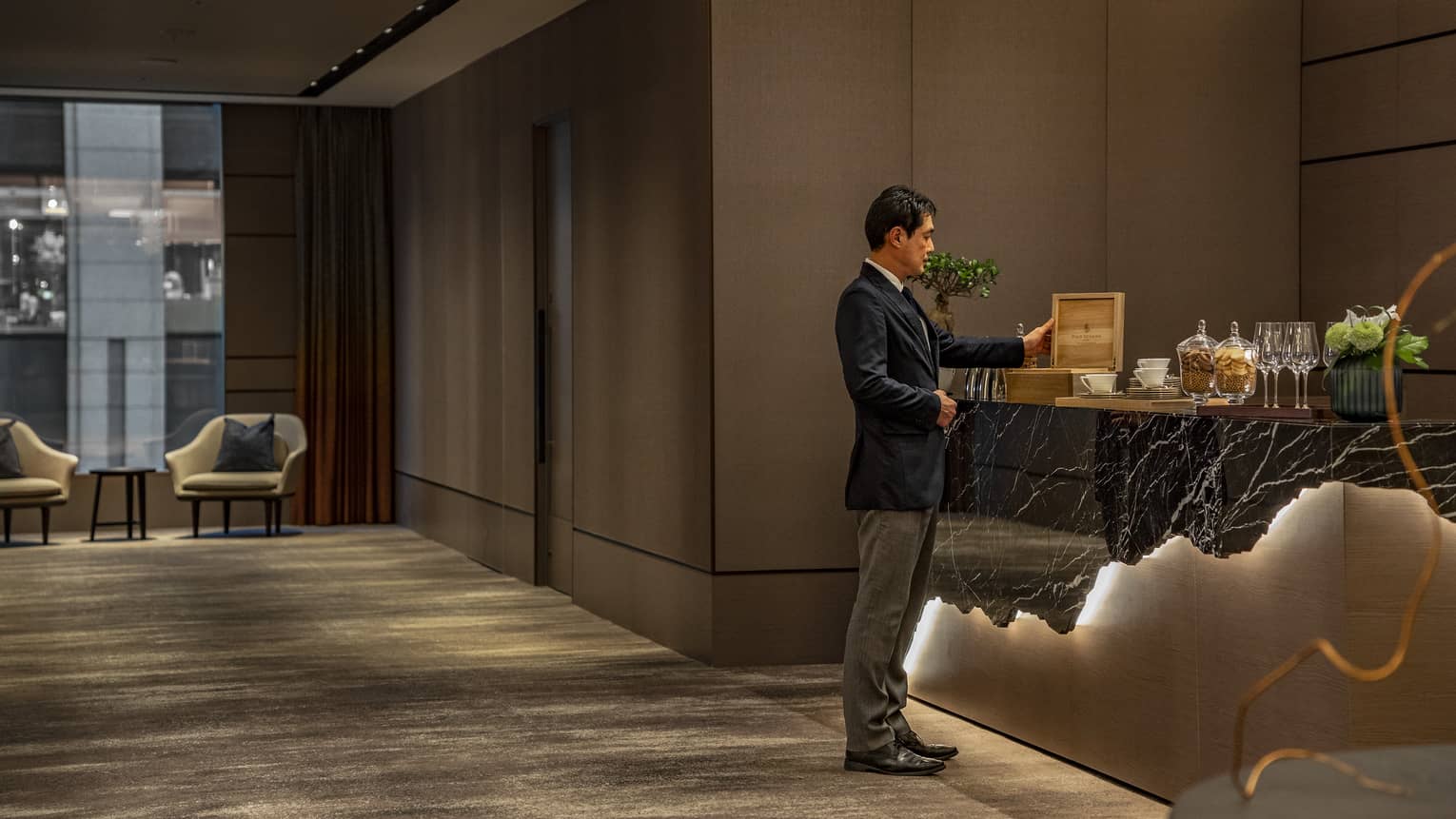 Male staff member replenishes the coffee and tea selection in the pre-function area outside a meeting room 