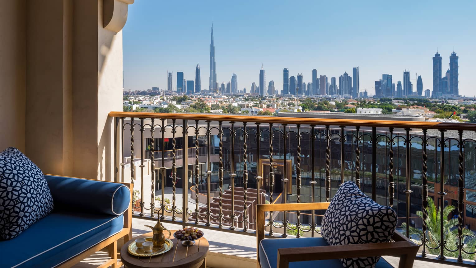 Premier Skyline Room balcony with wood patio loveseat and chair and blue cushions, city views