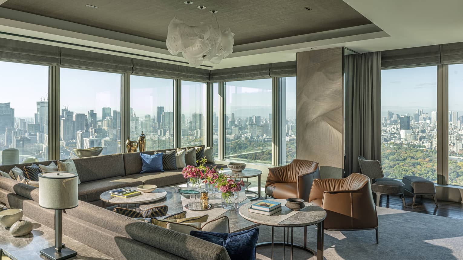 Elegant living room with large sectional sofa, two chairs, walls of windows, chandelier