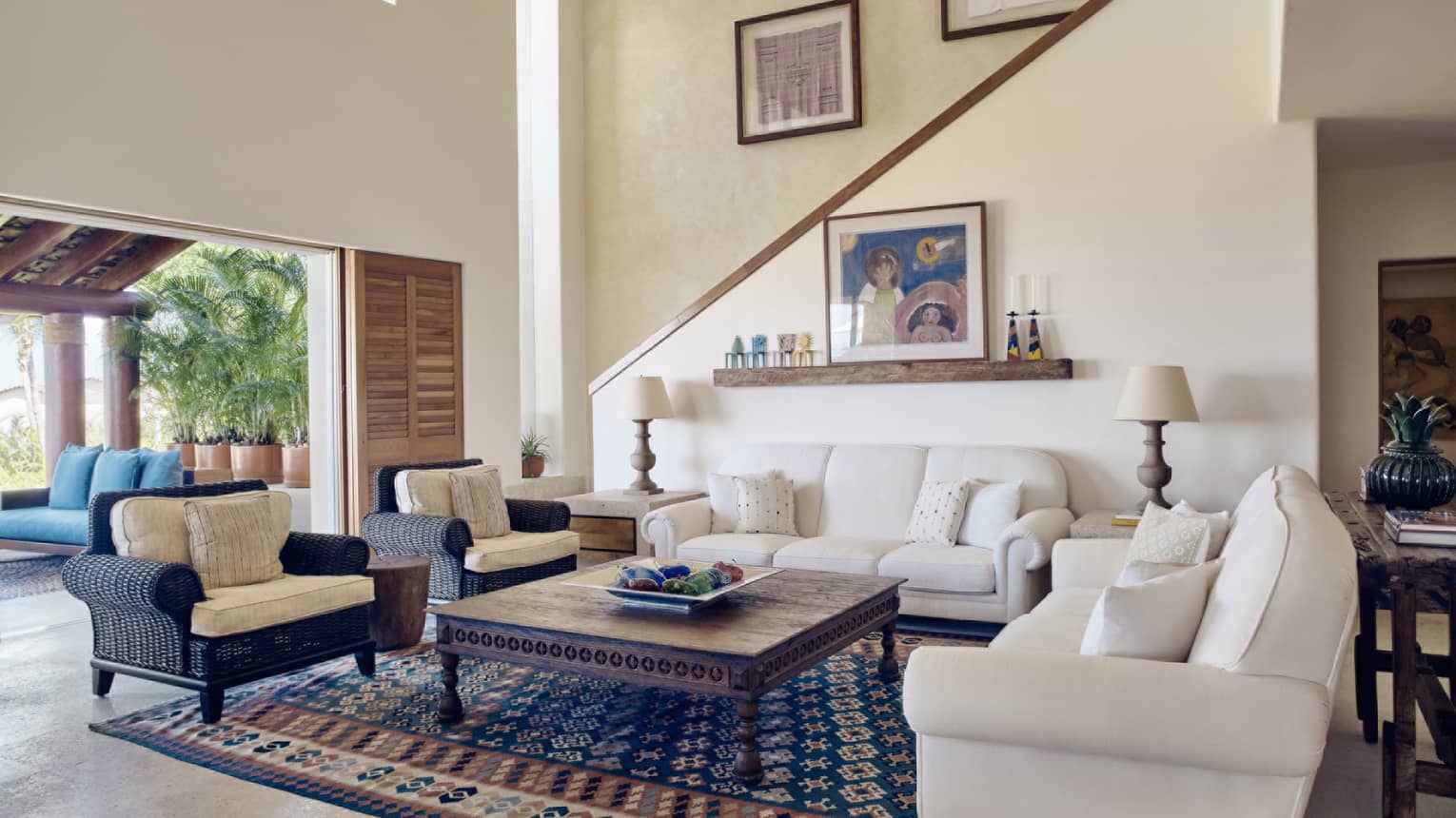 Living room with two white sofas, two arm chairs, stair case