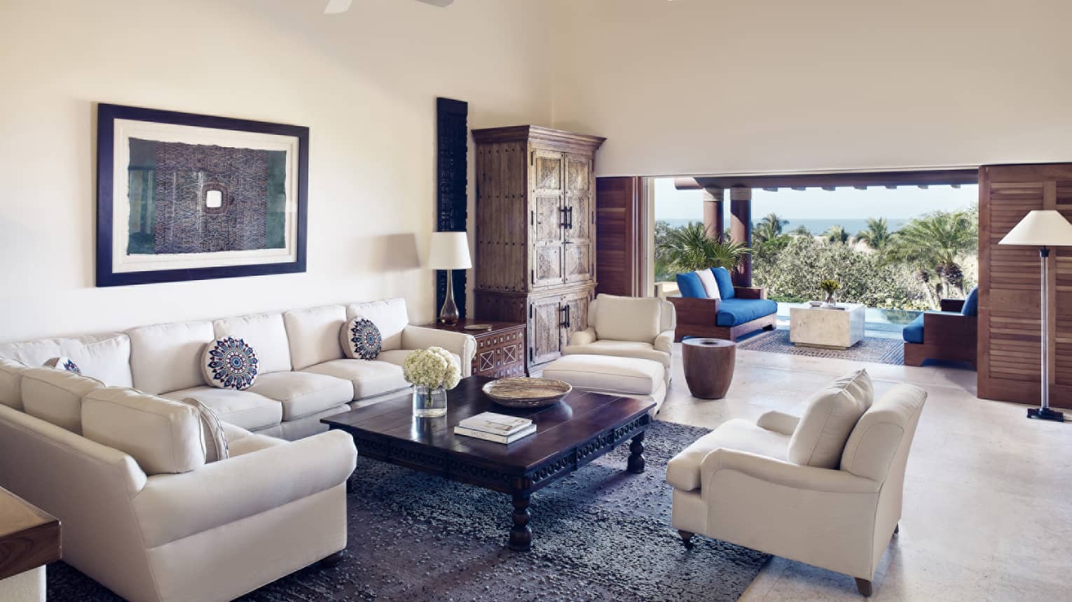 Living room with white sectional sofa and chair, blue rug, walk-out terrace