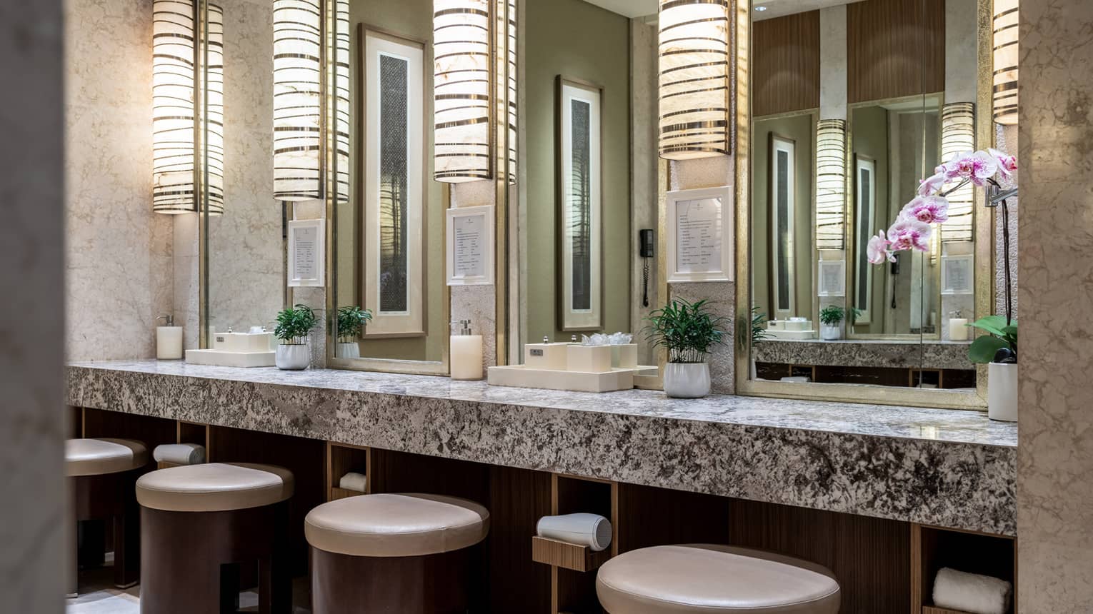 A modern spa vanity with rounded stools, rectangular mirrors and granite countertops