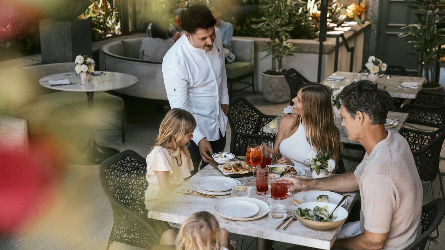 Family of four dines at a table on a restaurant terrace