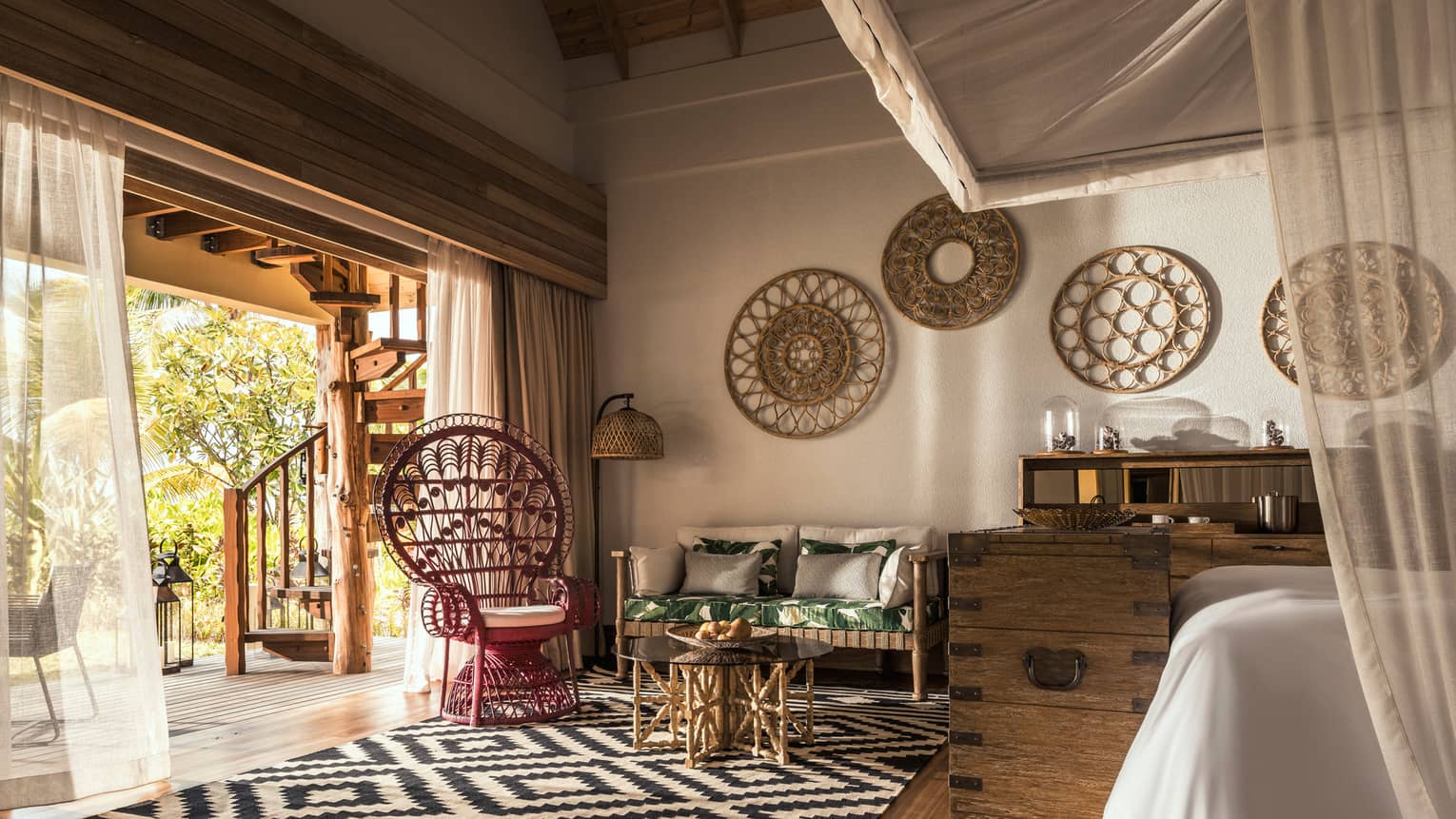 Coral Beach Villa open-air bedroom with black-and-white carpet, rustic wood furniture and art, long white curtains