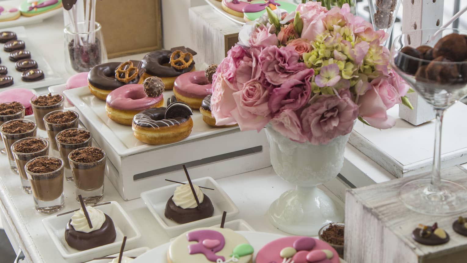 A table with cookies, donuts, cakes and bouquets of flowers