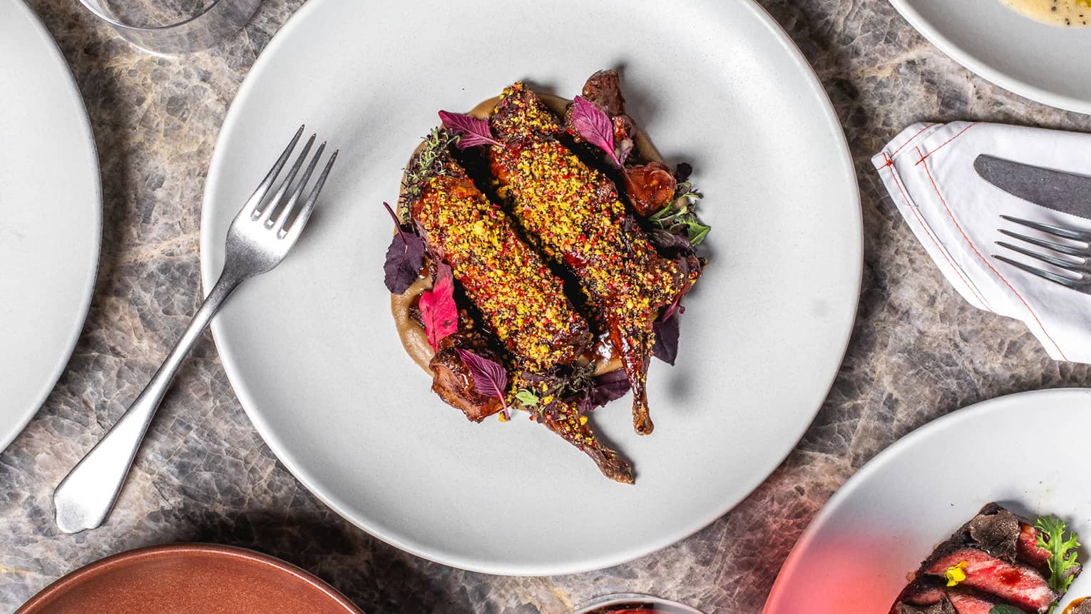 Plates of food on a table with wine glasses and silverware