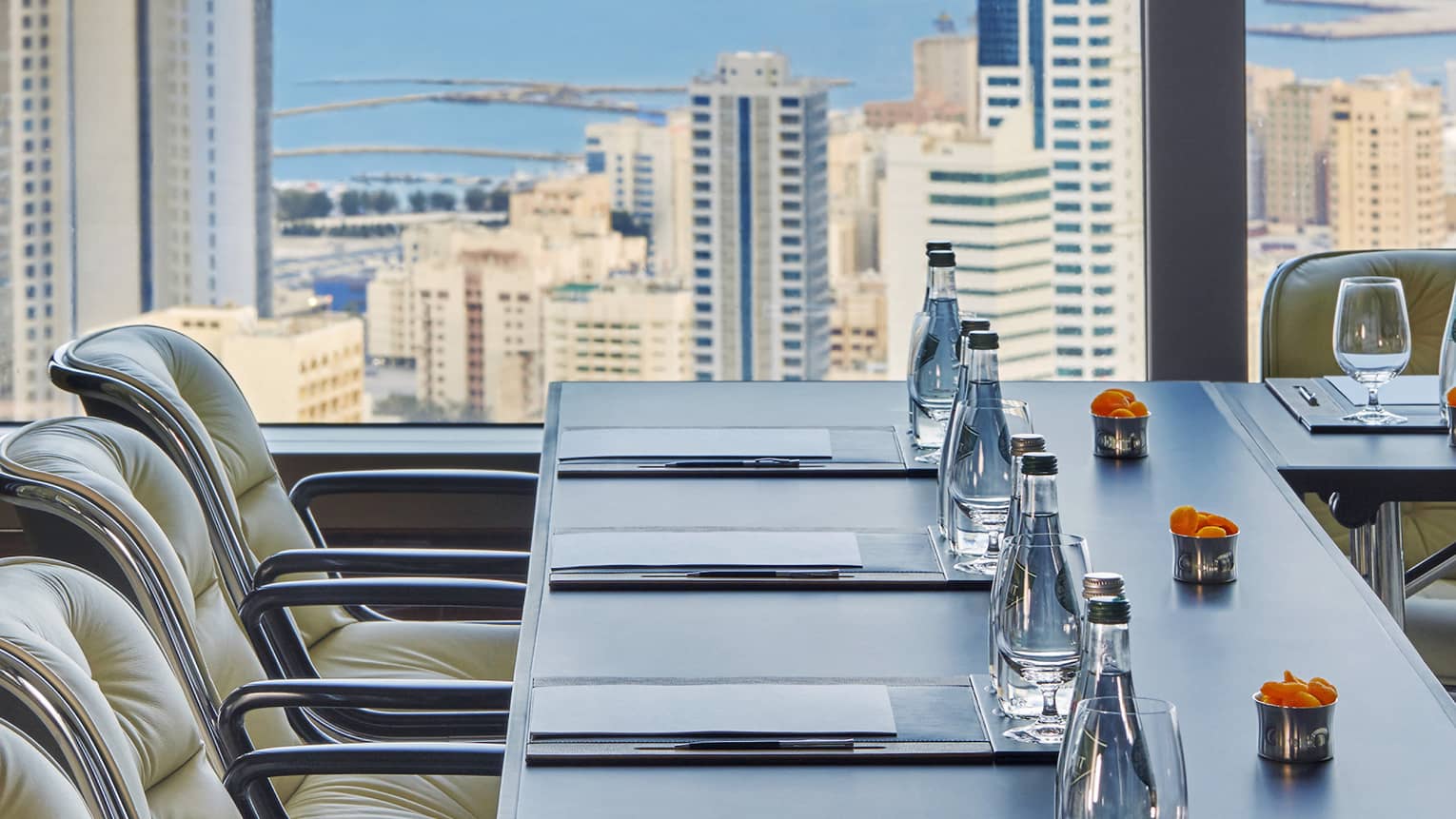 Close-up of meeting table with water, orange flowers by sunny window