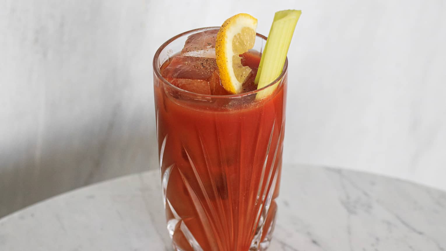 Bloody Mary in crystal highball glass with lemon slice and celery garnish