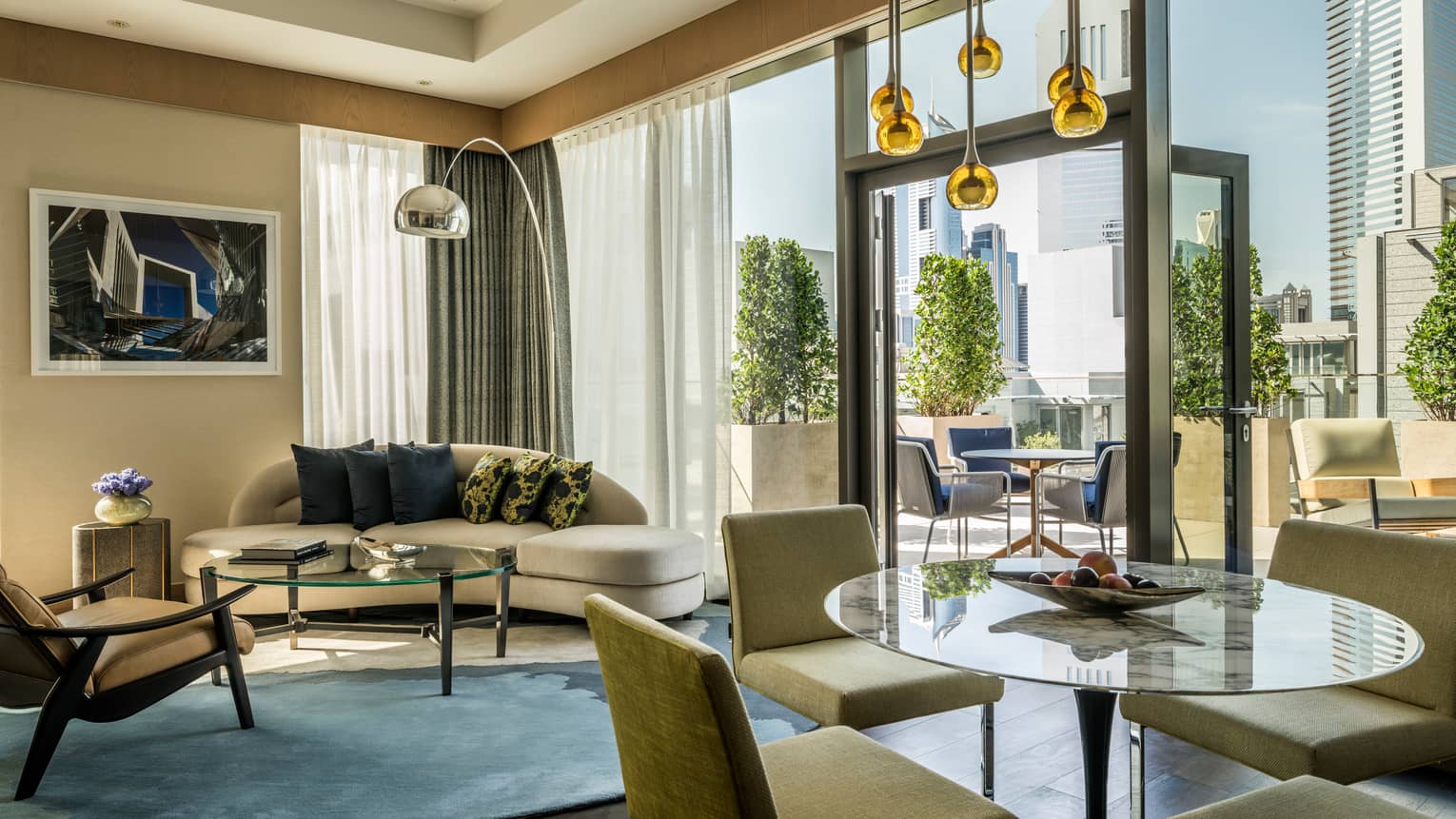Modern hotel suite living room sofa, glass tables and chairs, open glass door to patio