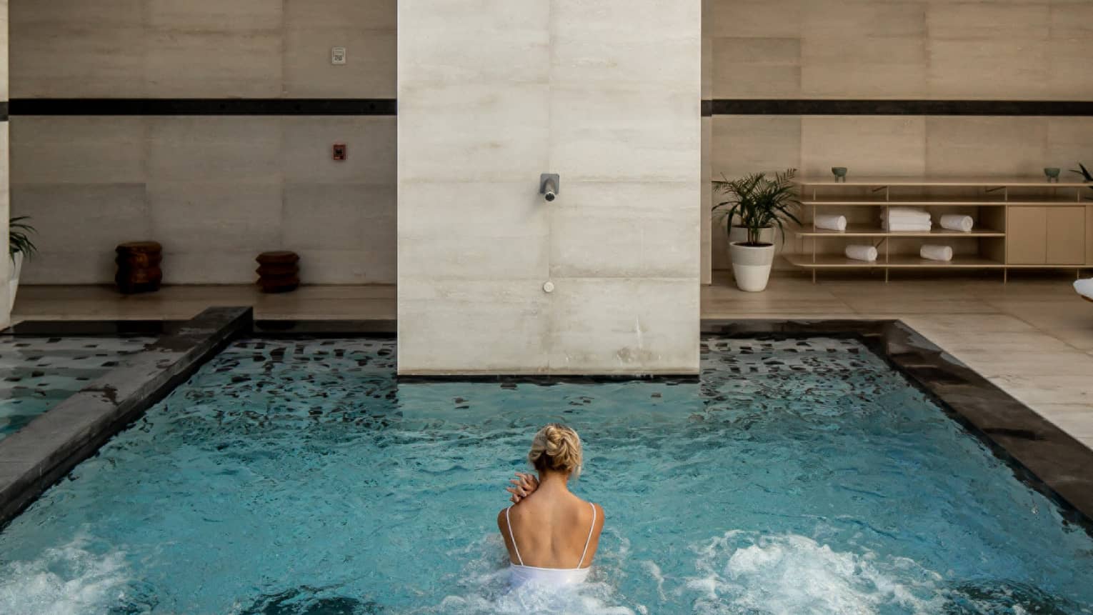 A person swimming in an outdoor pool with a sun roof.