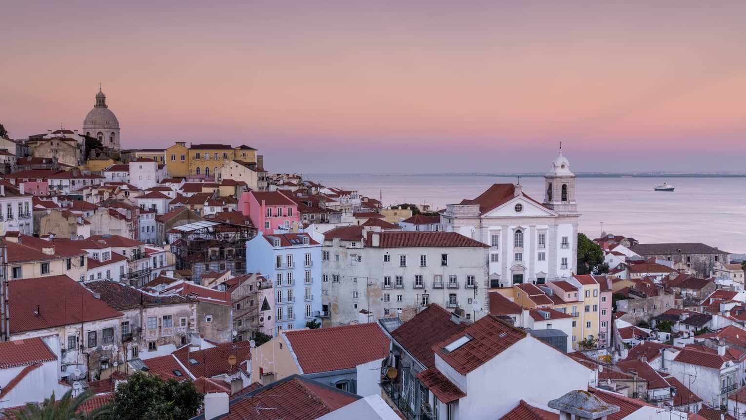 Aerial view of Lisbon traditional buildings with white houses, apartment buildings with brown roofs, white church