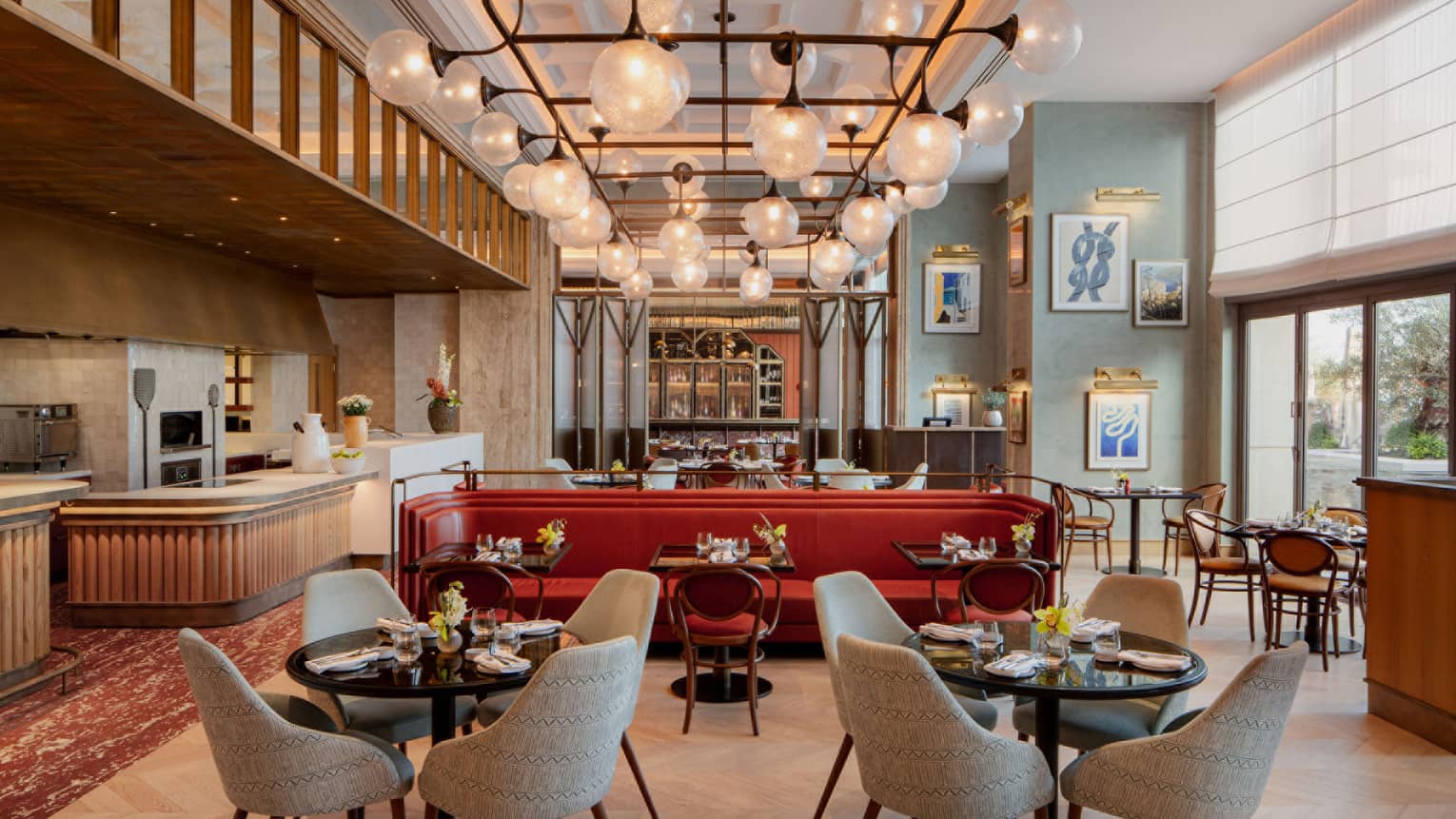 Indoor restaurant with red leather accent booth, tables of four, large bulb chandelier