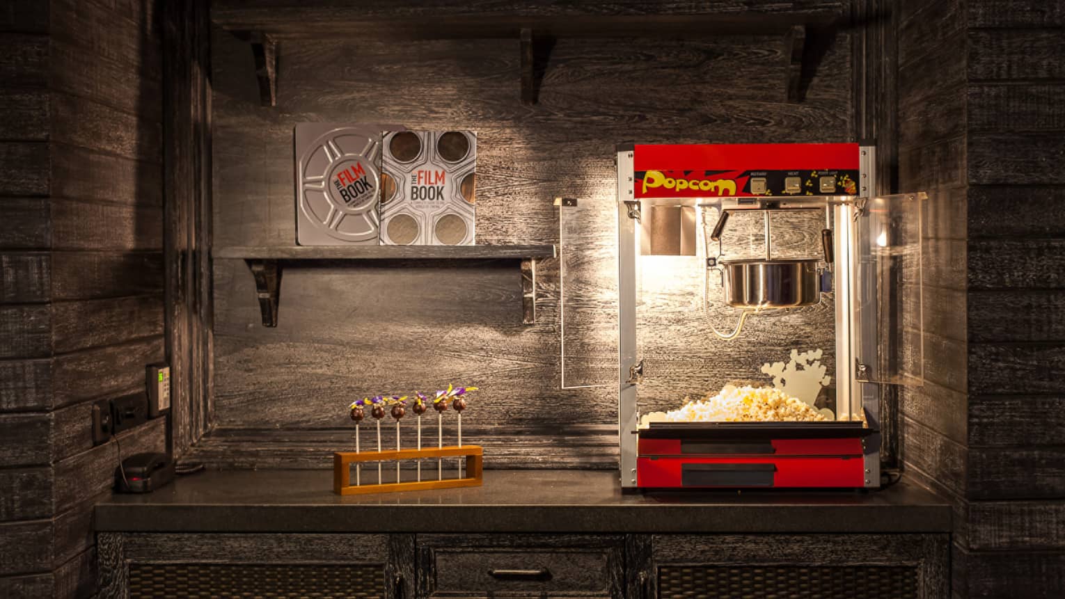 Popcorn machine, candy and film books on shelf in dark room