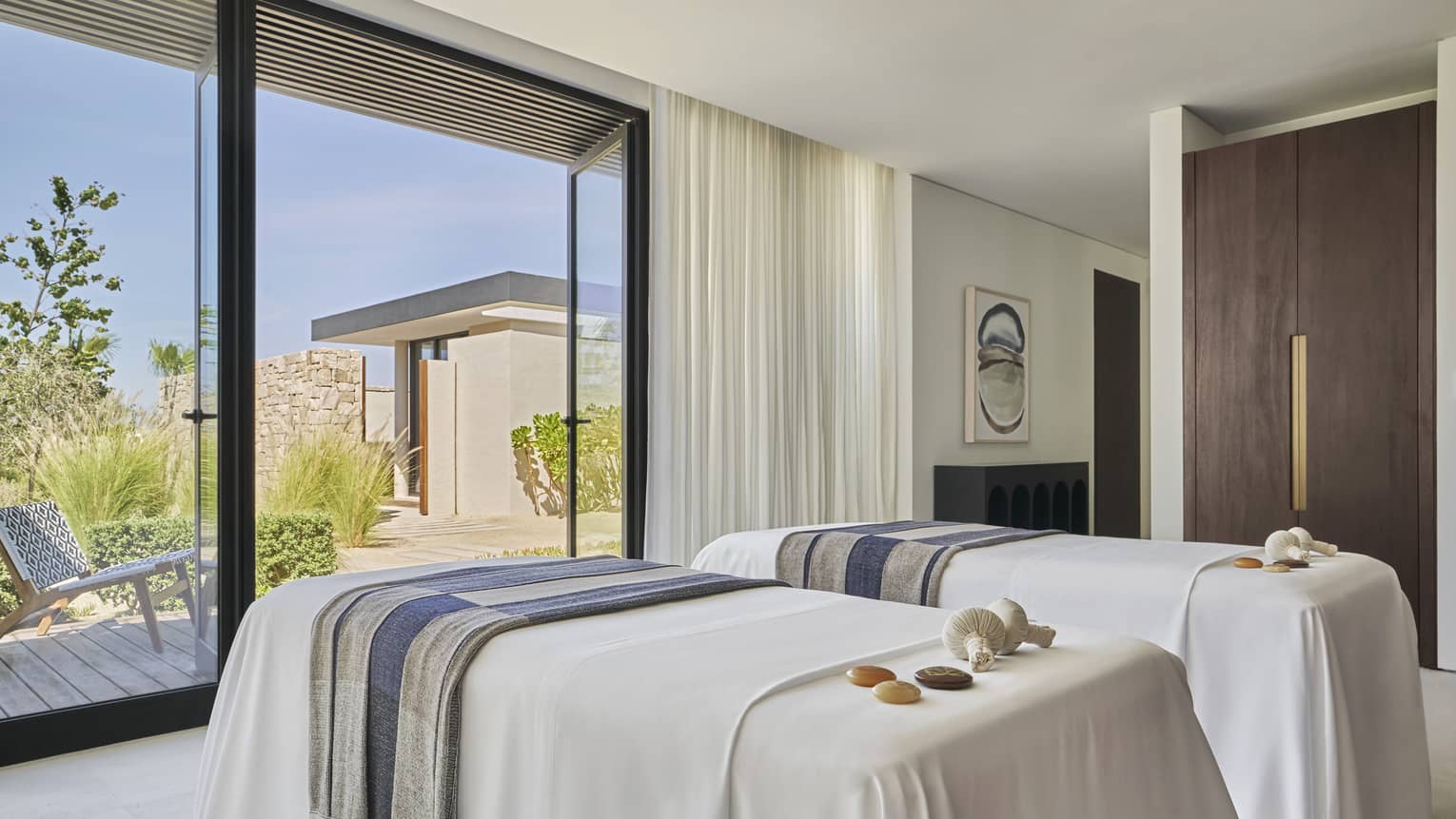 Two massage platforms facing a large window in a well lit room.