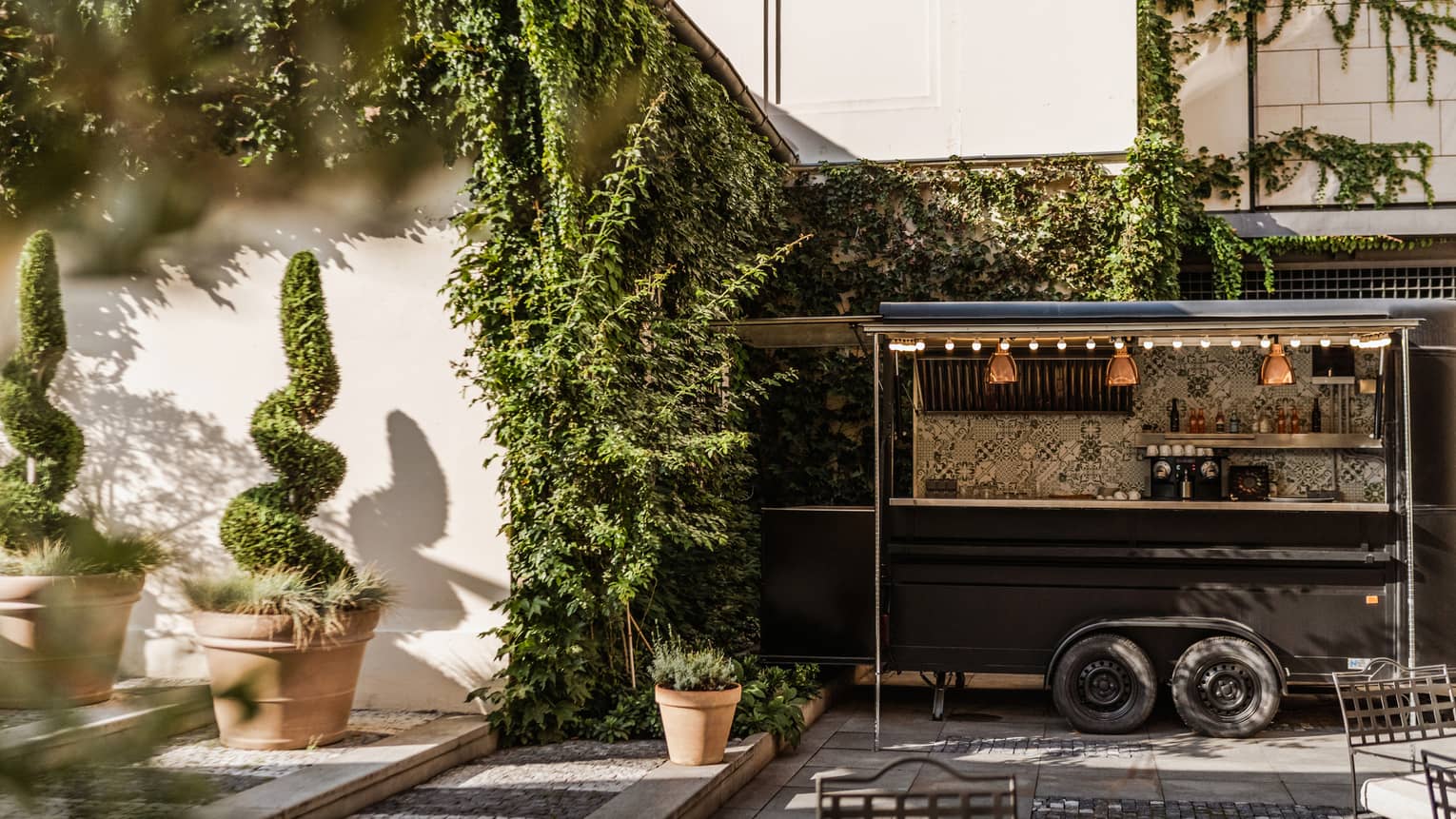 An outdoor event space with greenery-covered walls, decorative plantings and seating