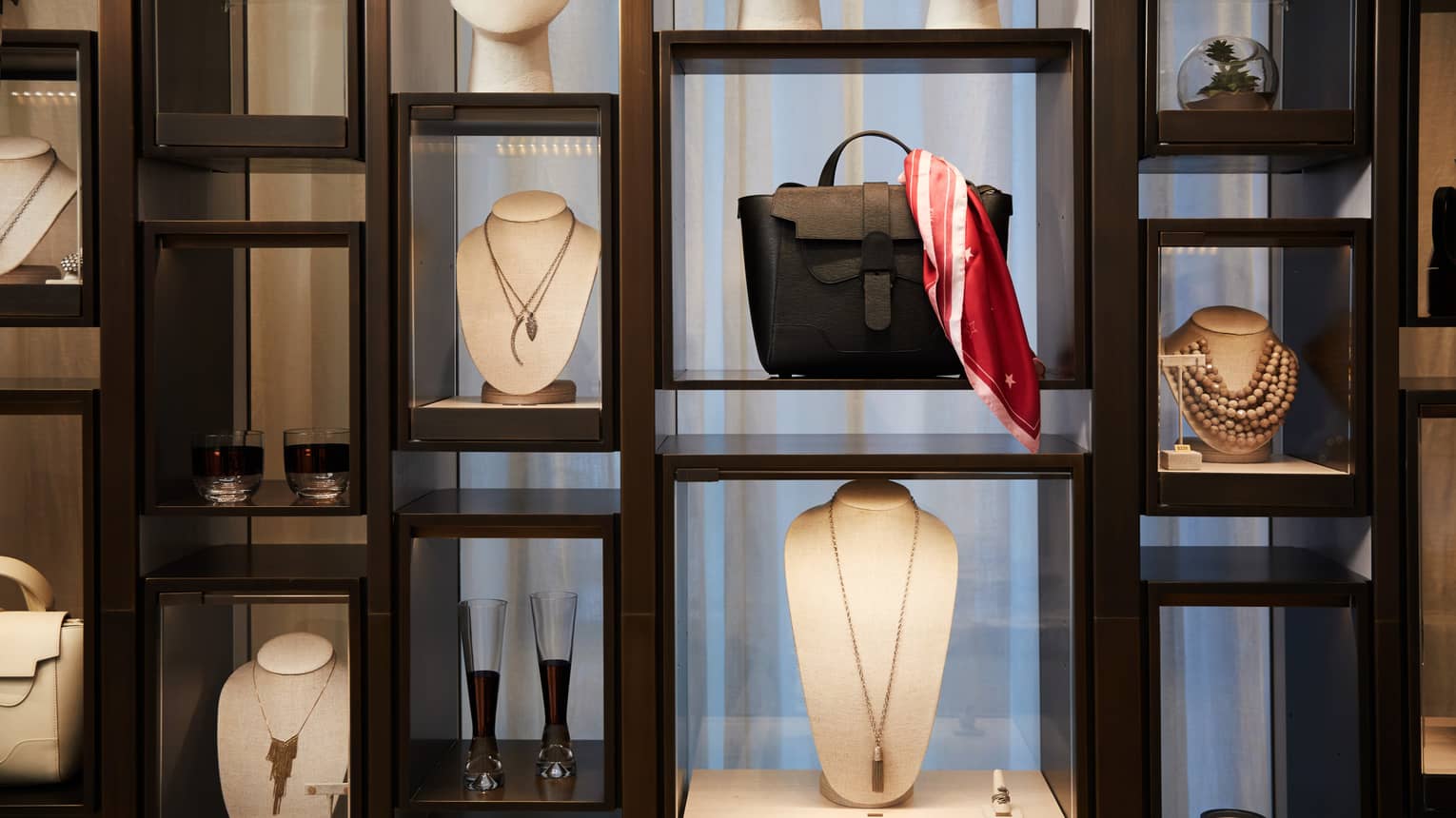 Boutique retail store shelf with designer necklaces, handbag, cocktail glasses