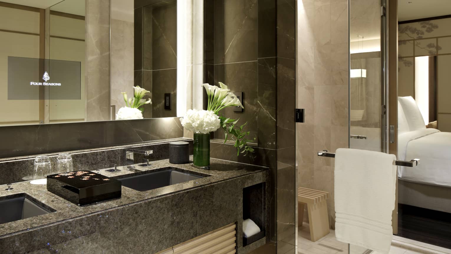 Luxury hotel bathroom with double sinks, marble countertops and fresh white flowers