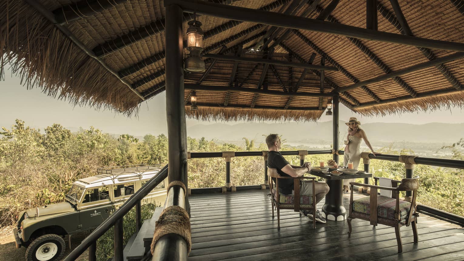 Couple enjoys Camp Peak Breakfast on platform patio near utility vehicle