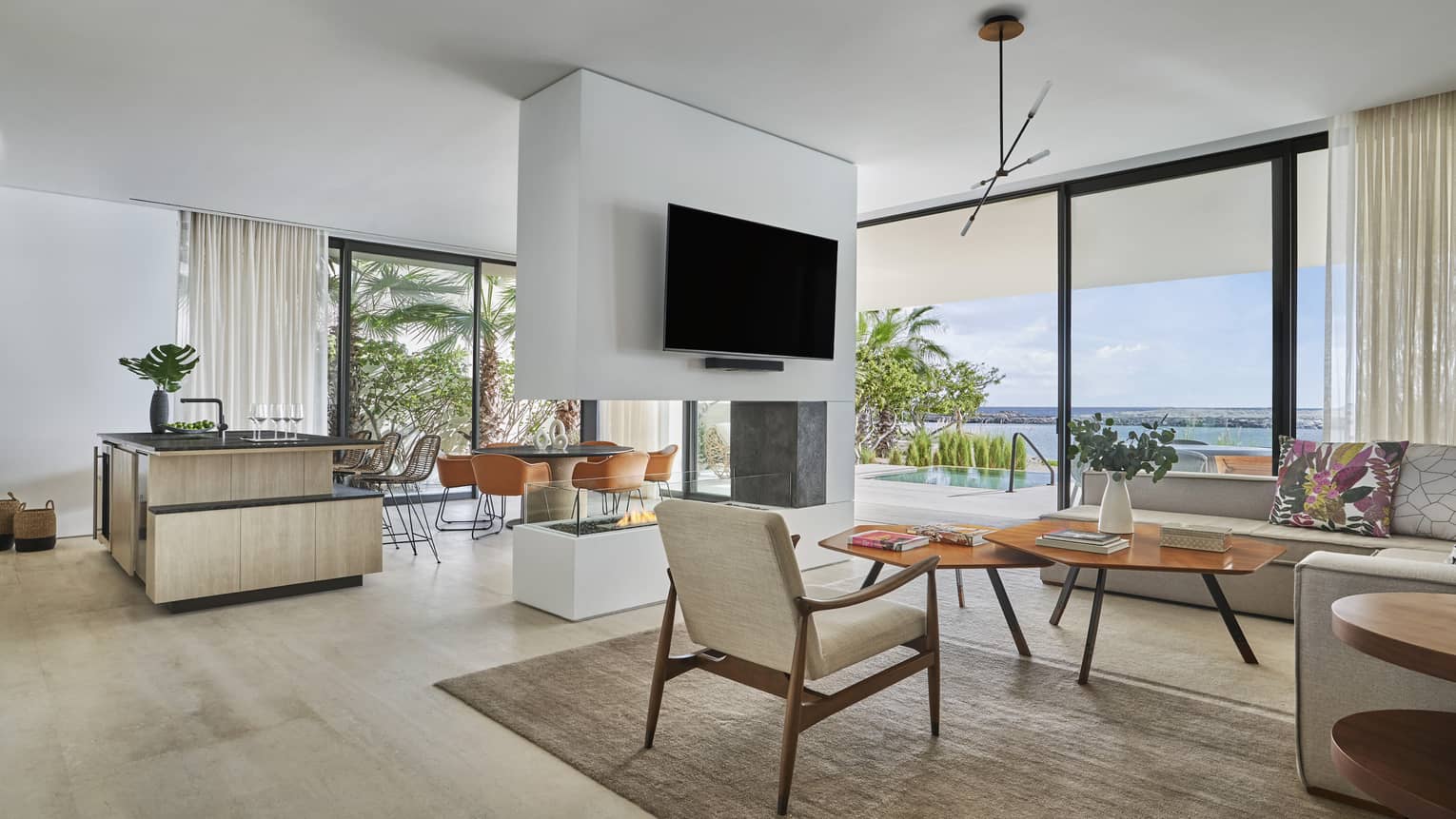 Open-concept living room, kitchen and dining room with modern fireplace in the middle