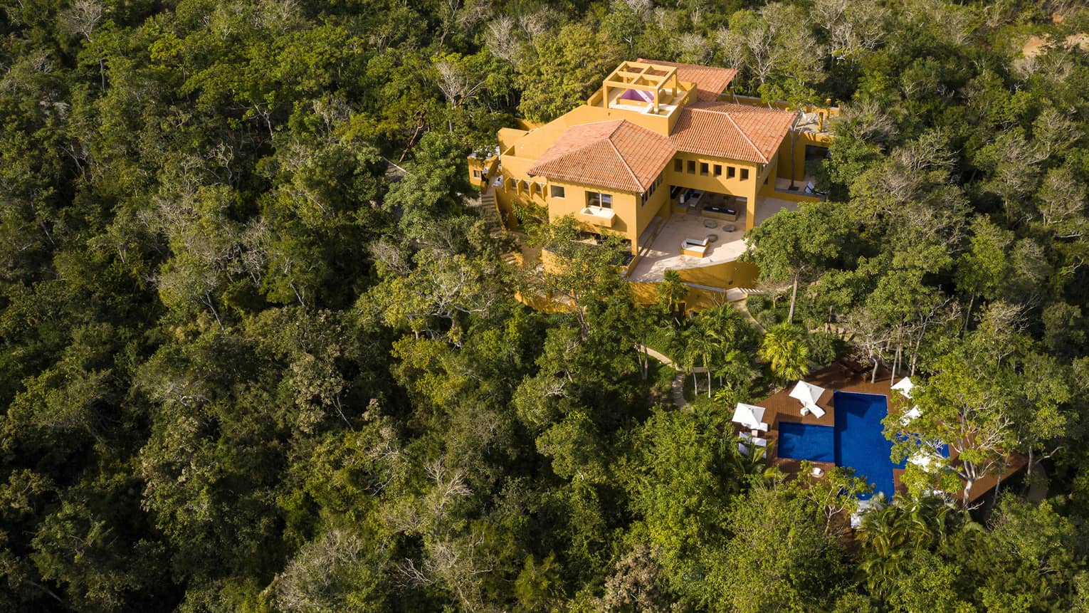Aerial view of private villa with pool surrounded by lush jungle trees
