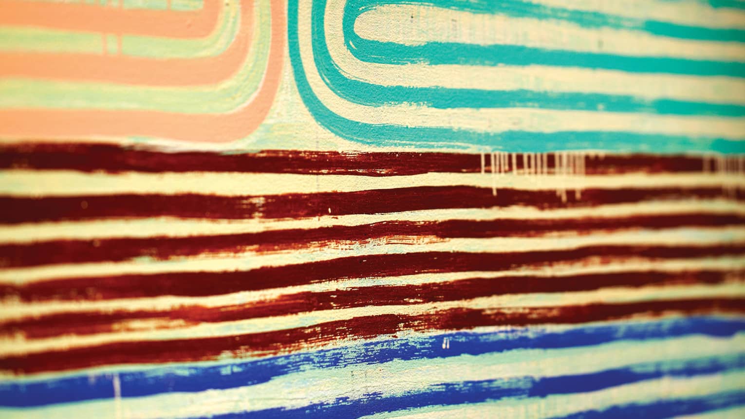 Close-up of pink, teal, red and blue lines of paint in pattern on canvas 
