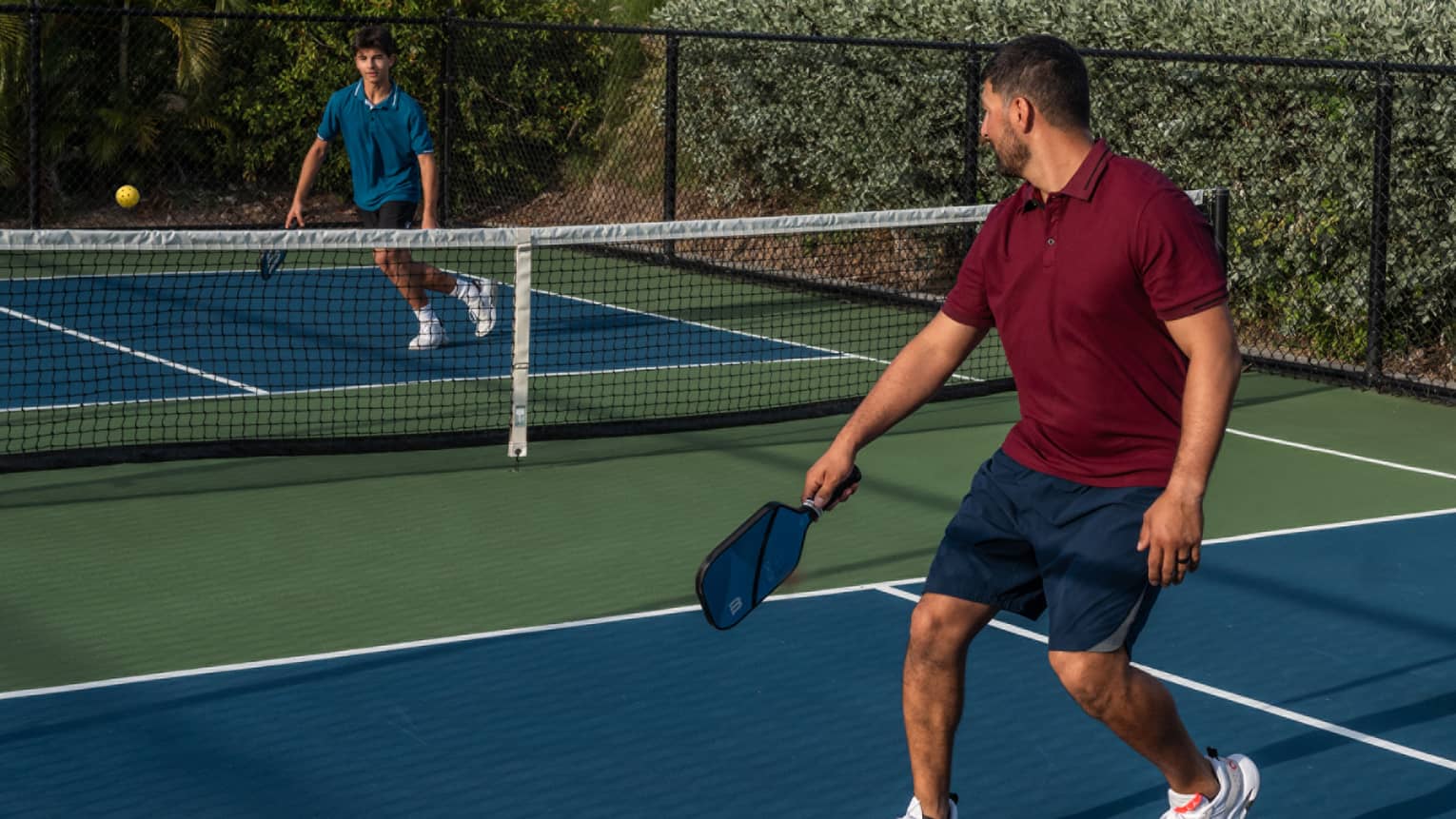 Guests playing pickleball on a pickleball court surrounded by palm trees
