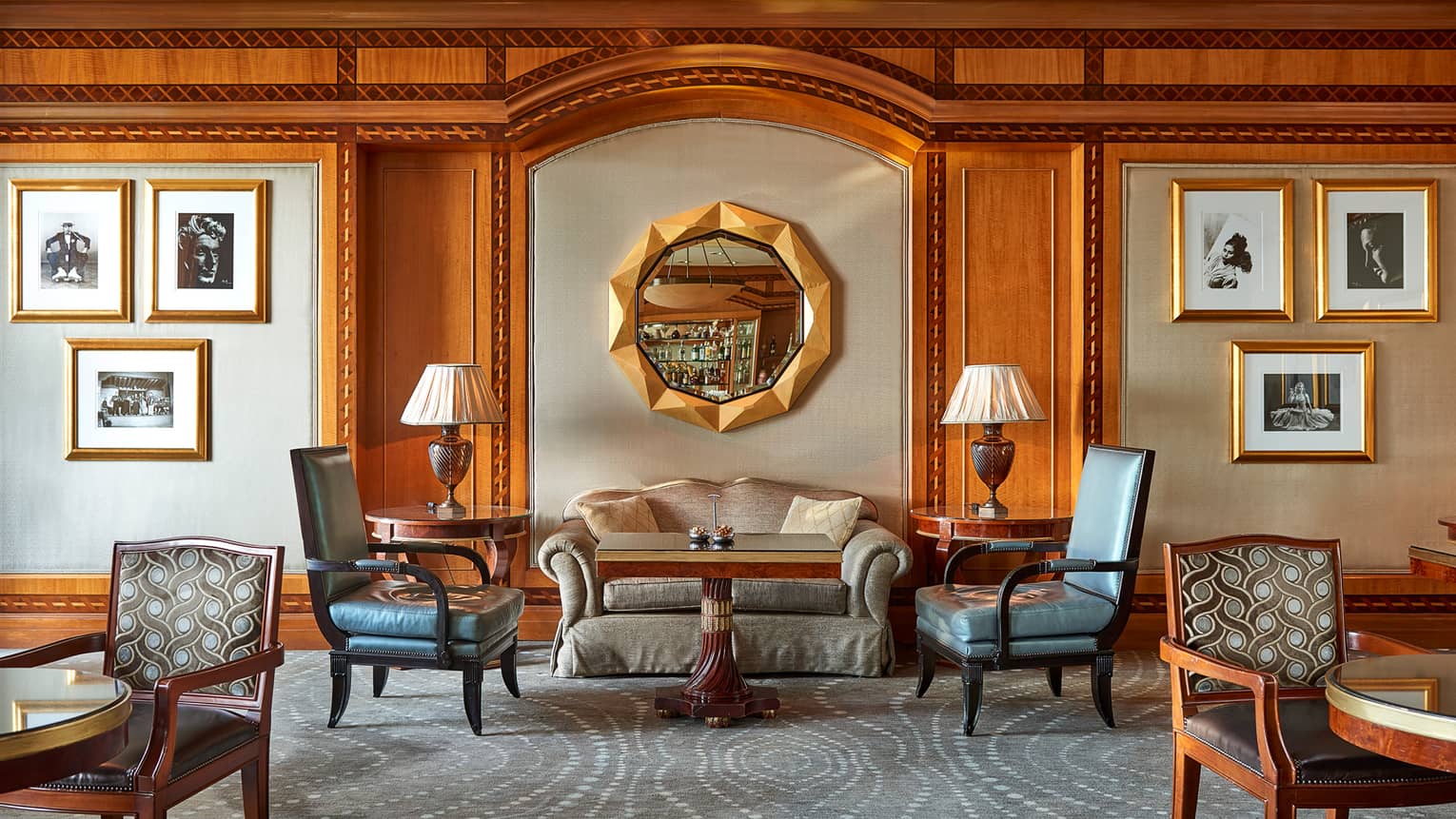 Lounge seating area atop blue carpet against wall with round mirror and artwork