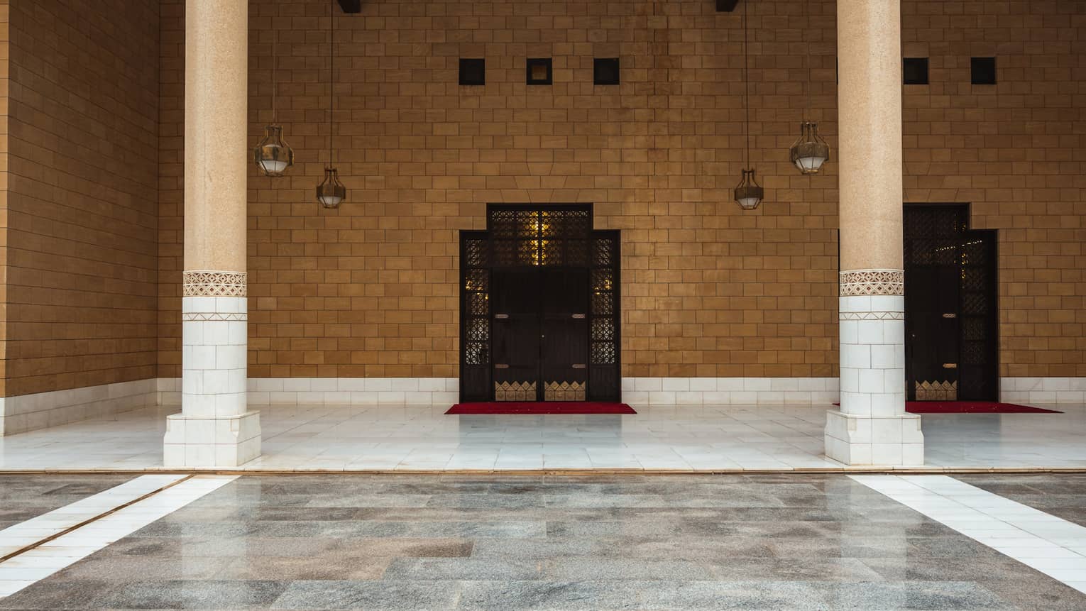 A brown stone wall with grey tile flooring.
