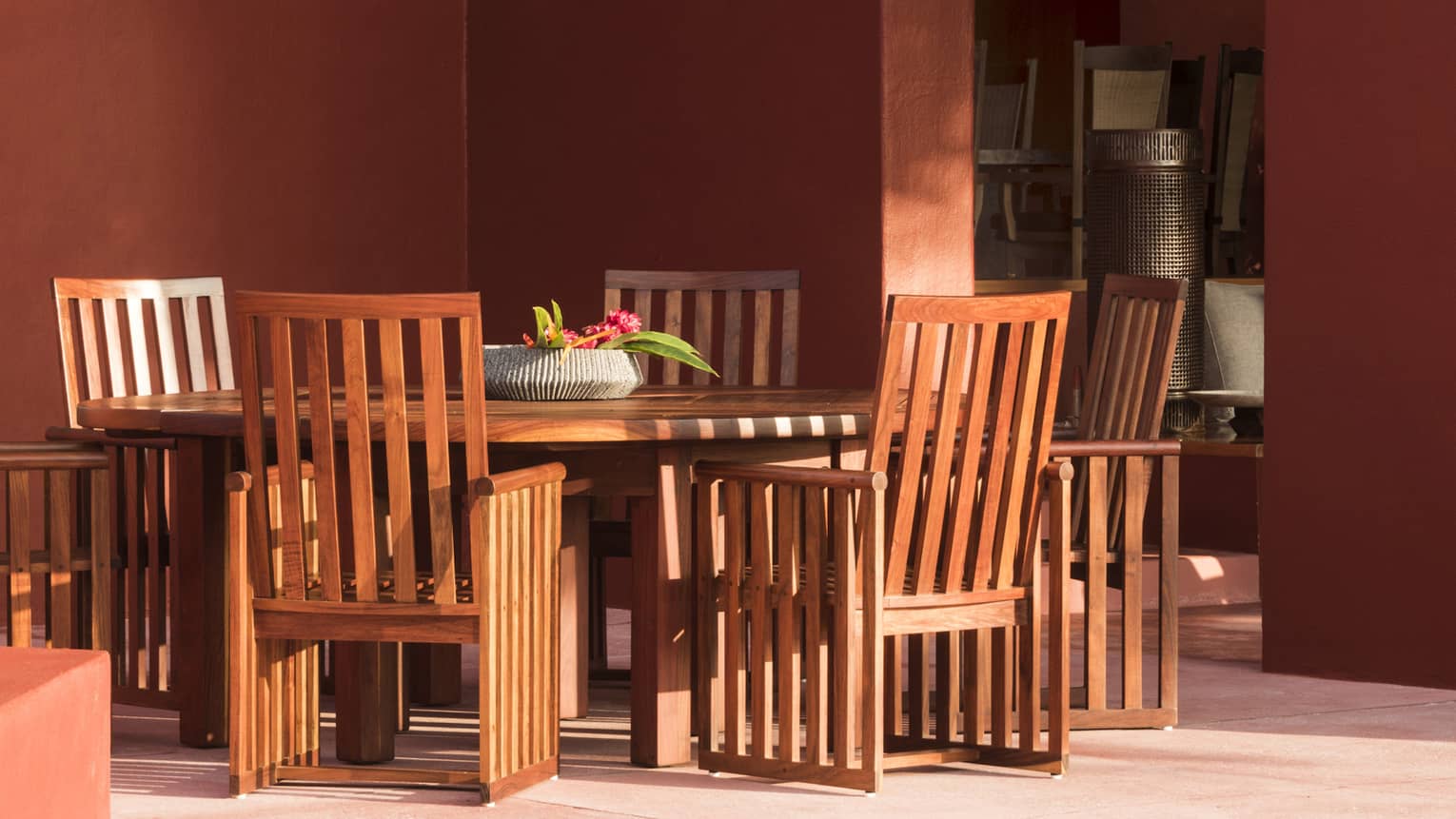 Patio with red-washed concrete floor and wooden dining table