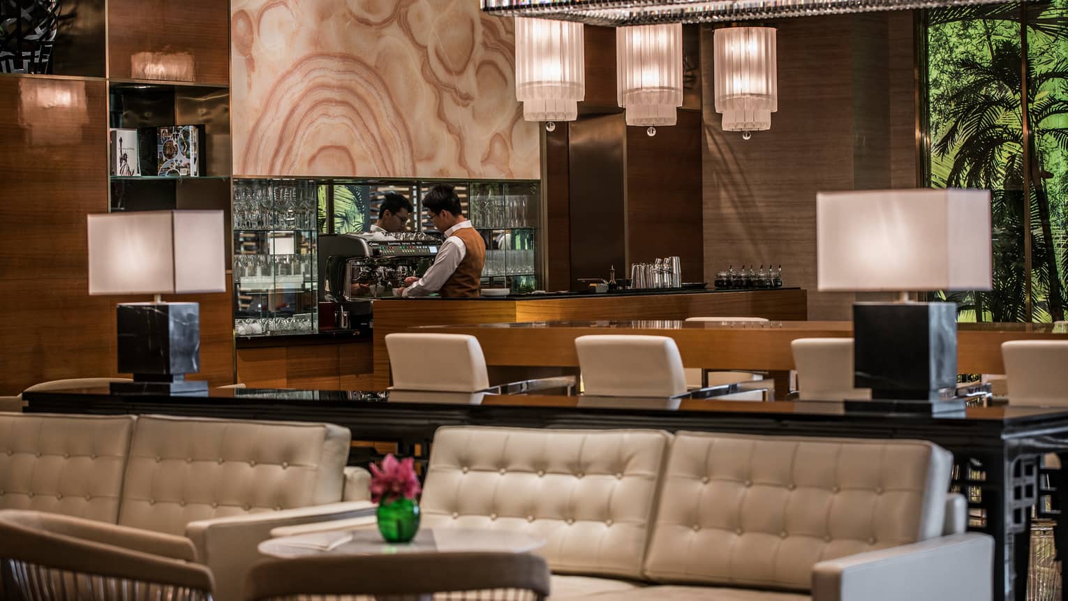 La Sala staff makes coffee at espresso machine behind wood bar, white leather banquettes