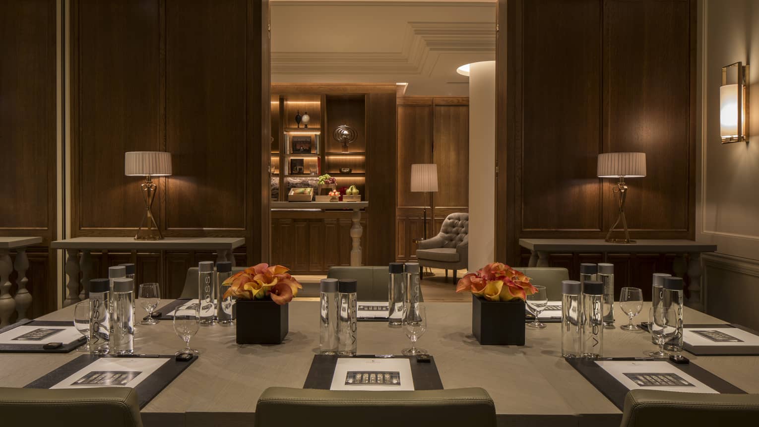 Serica Meeting Room with wood panel walls, rectangular boardroom table set with agendas, water 