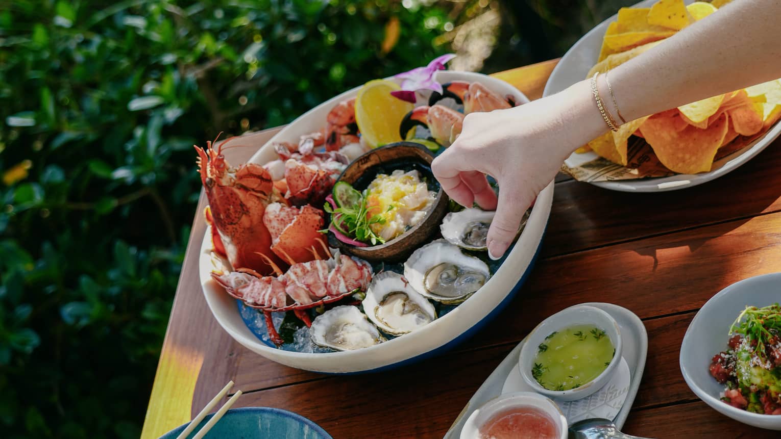 Outdoor table filled with various plates of food, including a large bowl of fresh seafood