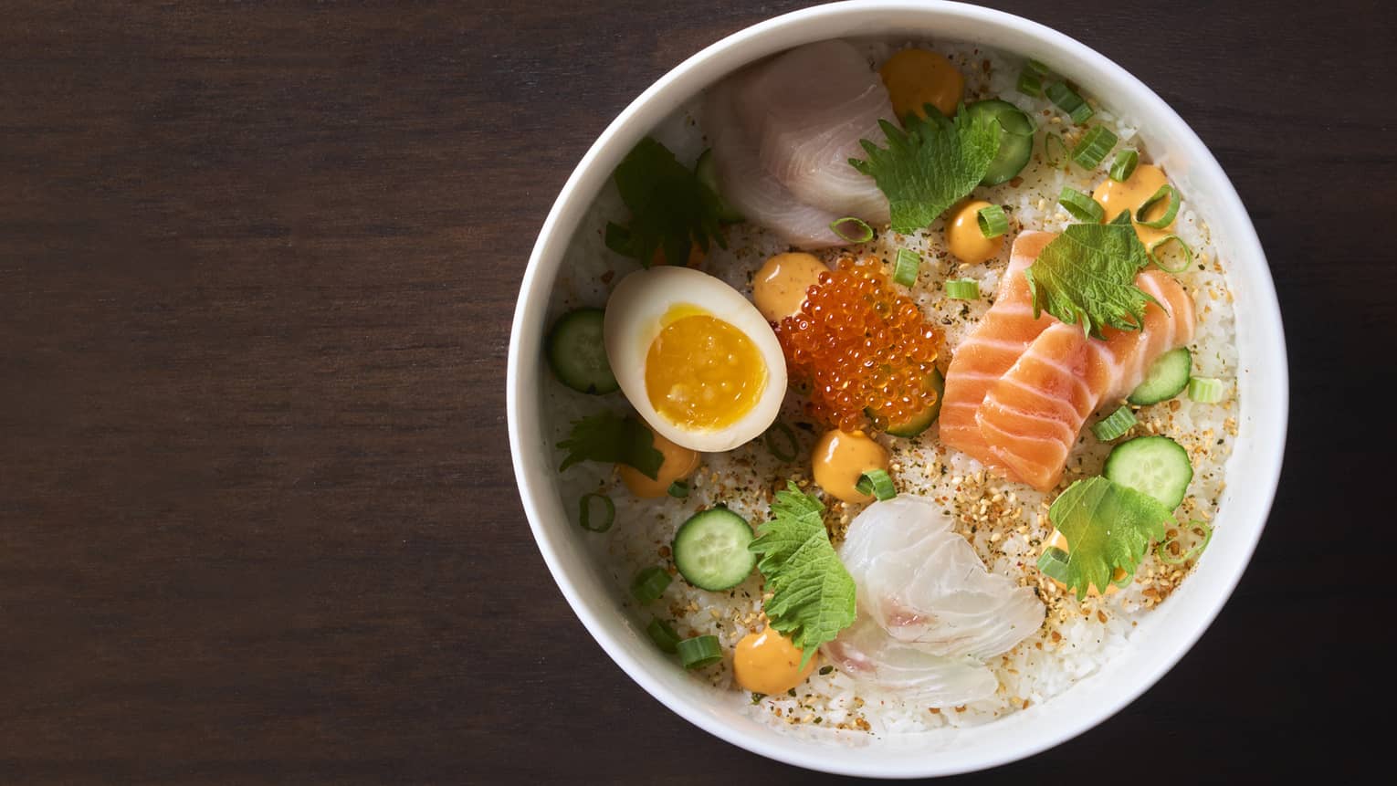 Various fish, herbs, and an egg in a bowl.