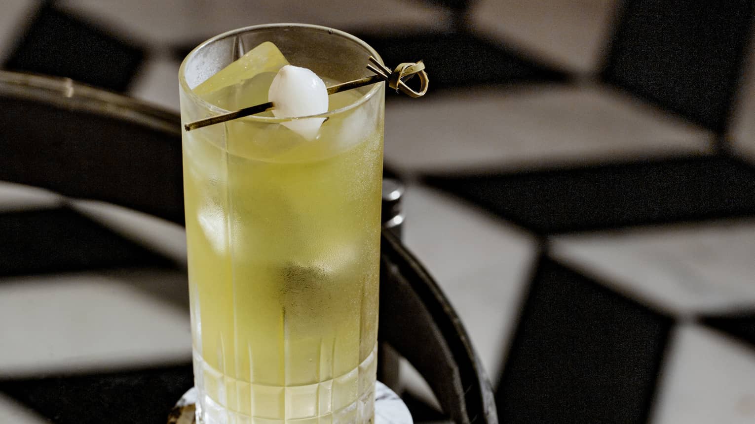 A yellow cocktail on a glass table.