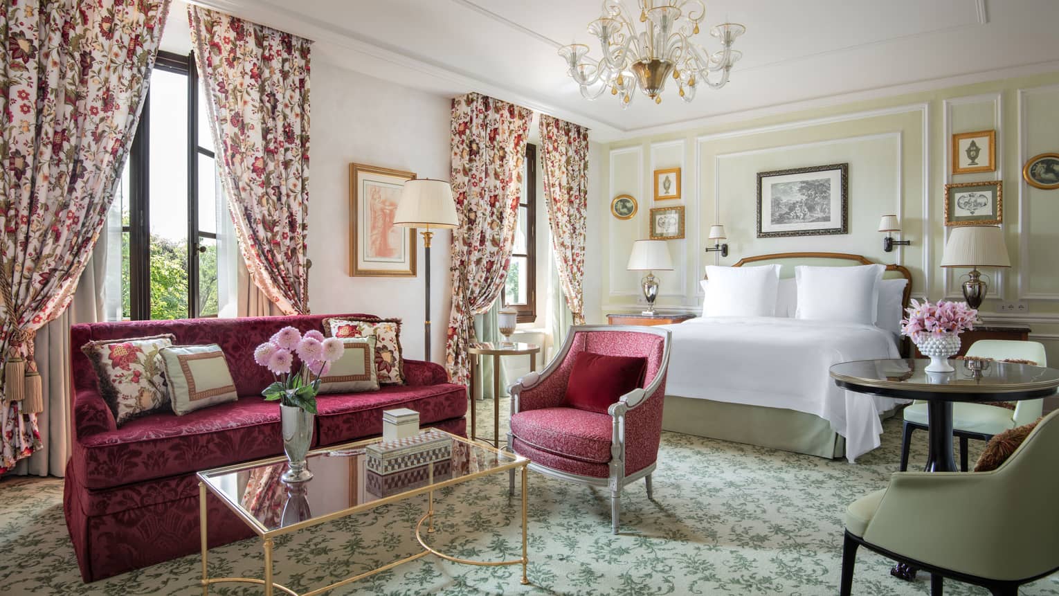 Luxury hotel room with king bed, ruby-bed sofa and chair, chandelier and window curtains at Four Seasons Hotel Florence