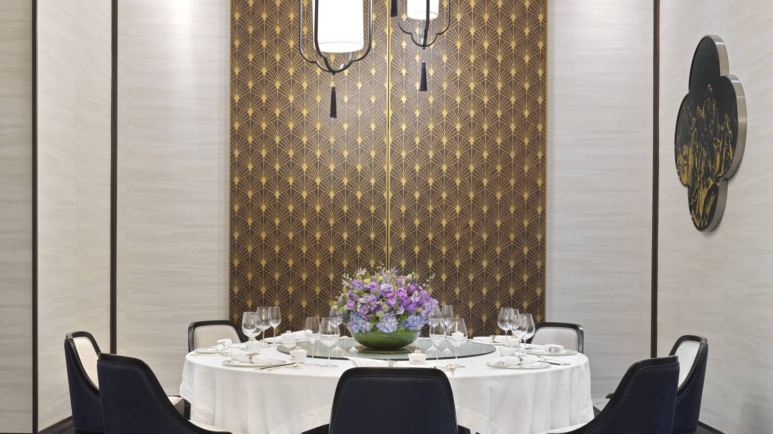 Zi Yat Heen private dining room with round table and white linens, eight blue chairs, watercolour carpeting, triple light fixtures from ceiling