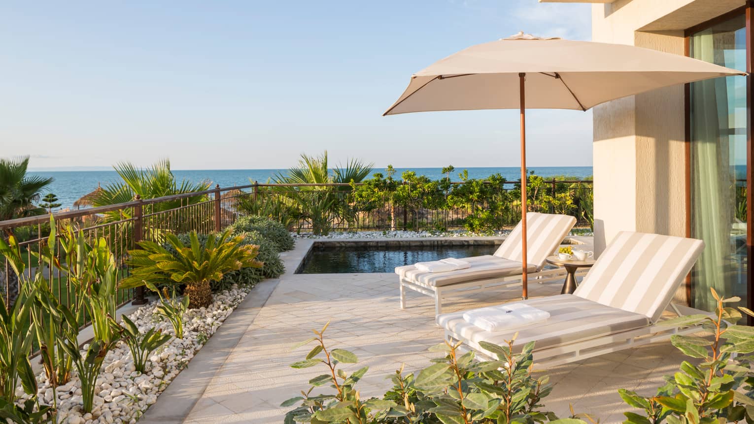 Mediterranean Suite Terrace, two patio lounge chairs and umbrella next to plunge swimming pool, tropical gardens