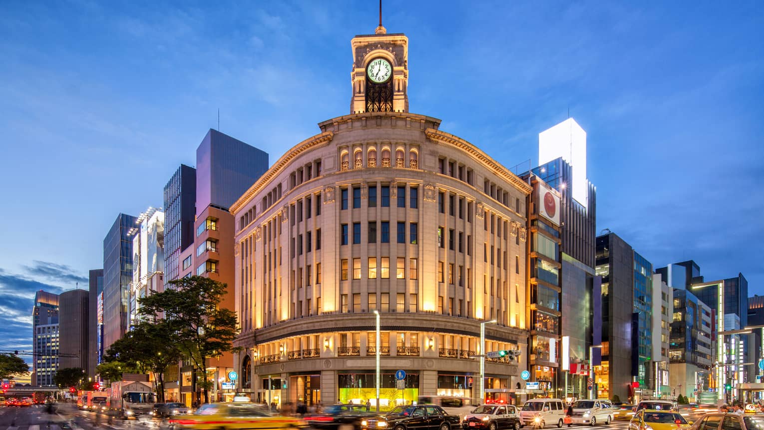 Illuminated historic building with a clock tower in a bustling city centre