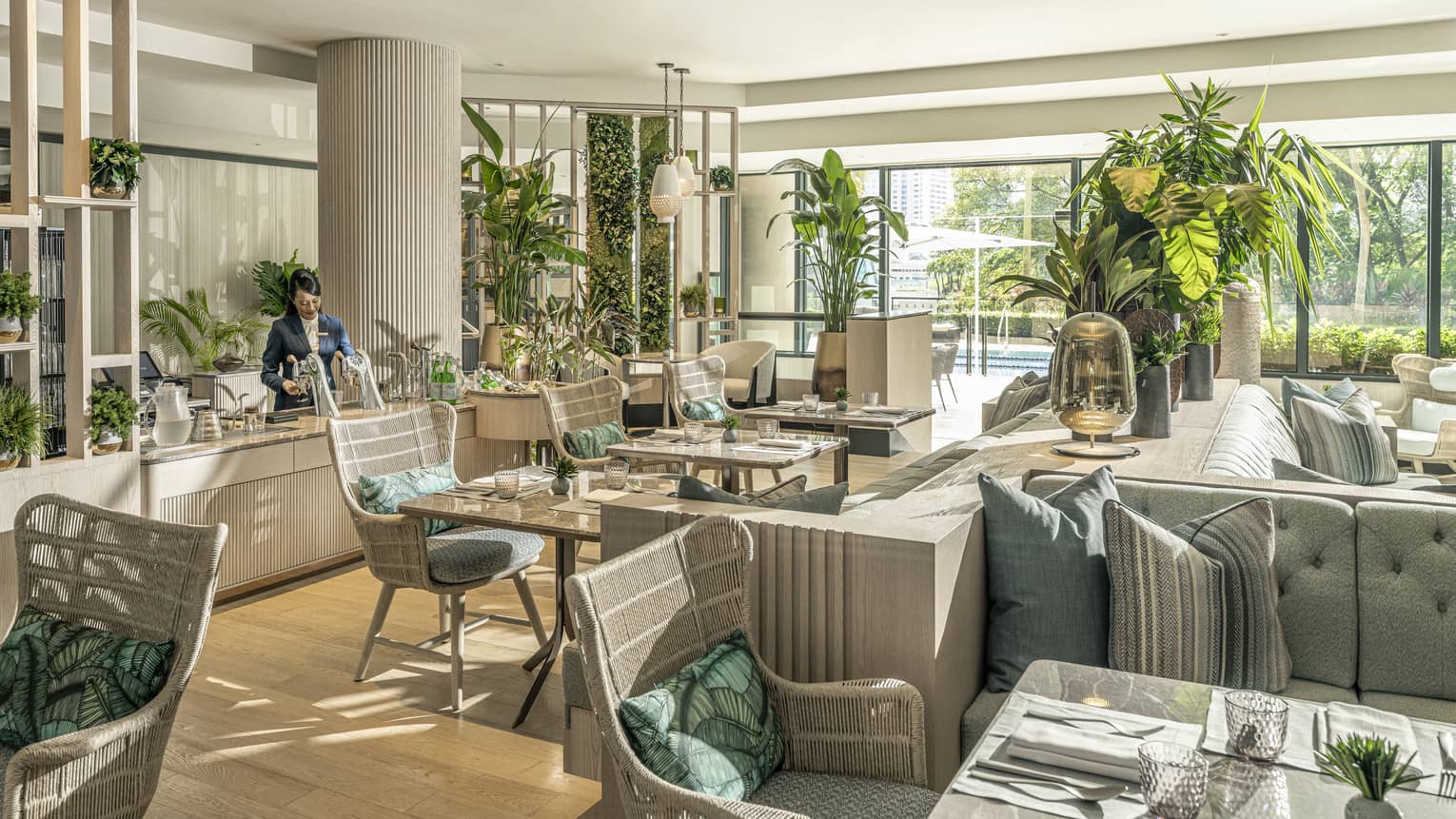 Pool House dining area with natural light, potted palms, rattan chairs and light blue sofas